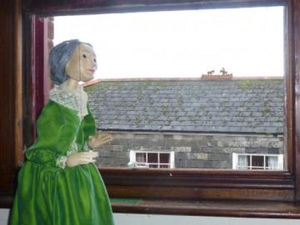 Enys Tregarthen puppet looks out of Padstow museum window at Little Horsemen on a rooftop