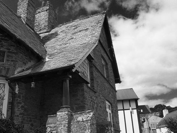 monochrome image of Gothic influenced cottage with dramatic sky behind