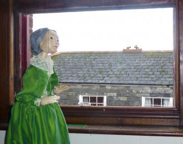 Enys Tregarthen puppet looks out of Padstow museum window at Little Horsemen on a rooftop